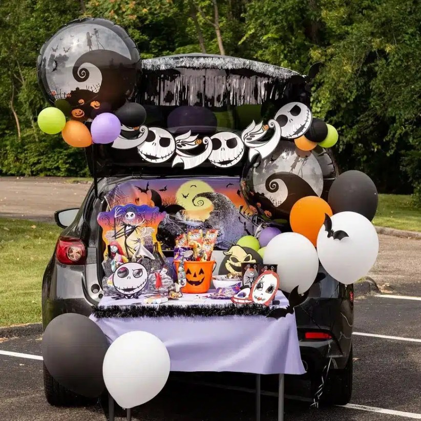 Car trunk filled with The Nightmare Before Christmas decorations, Jack Skellington faces, Halloween balloons, and a candy table covered in purple.