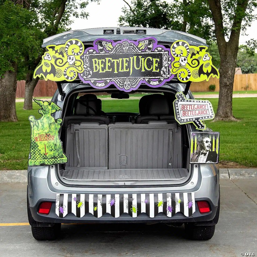 SUV trunk decorated with Beetlejuice signs, spooky green and purple graphics, and striped hanging fringe for a themed Halloween trunk display.