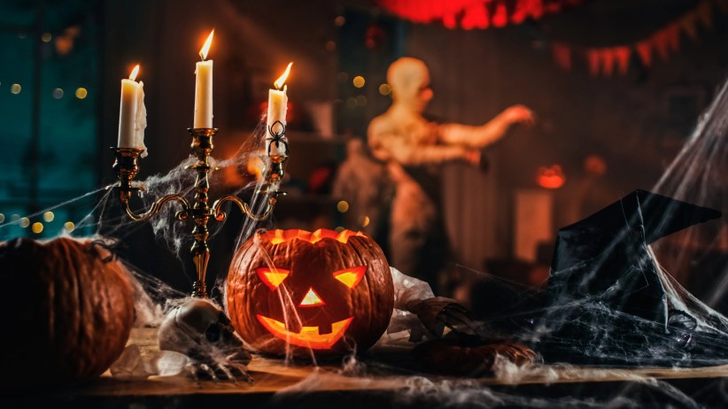 Glowing jack-o’-lantern surrounded by candles and cobwebs, eerie haunted-house vibes — Haunted Houses in New York