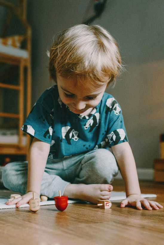 little boy spinning a dreidel on Hanukkah