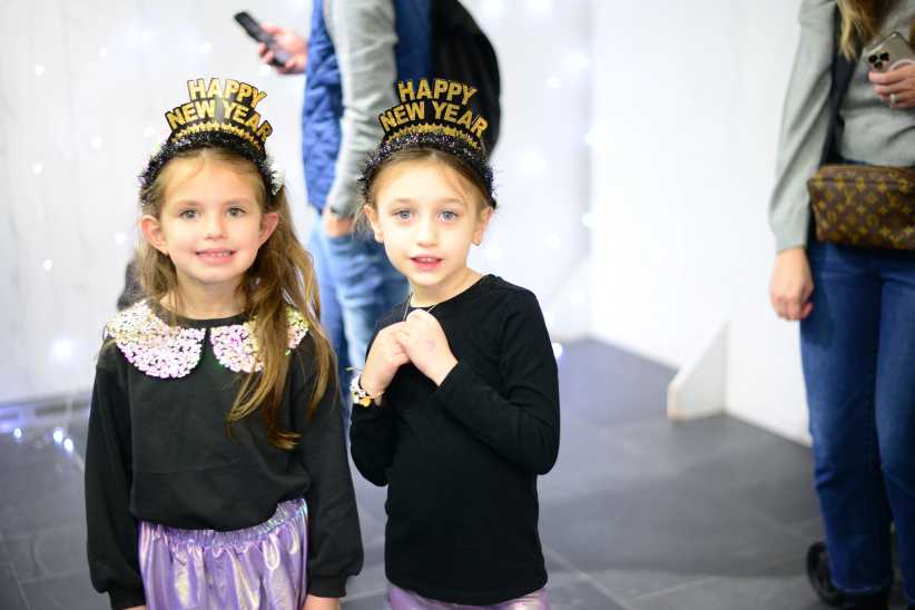 two young girls wearing black and gold "happy new year" hats. 