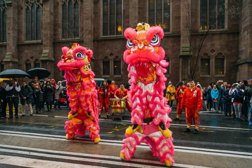Two dancers performing the lion dance on the street. 