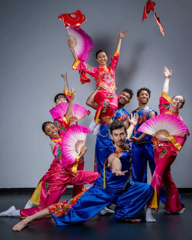 Dancers with fans dressed in pink and blue.