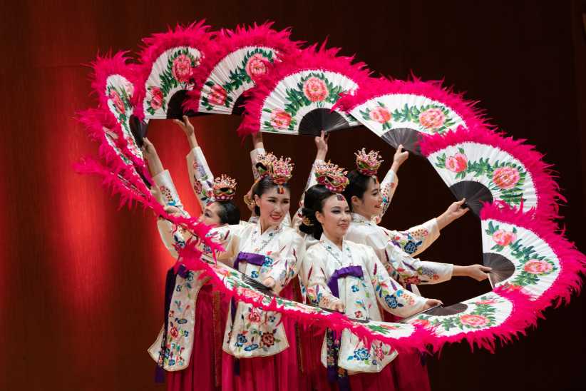 Woman dancing with fans during a traditional Lunar New Year performance. 