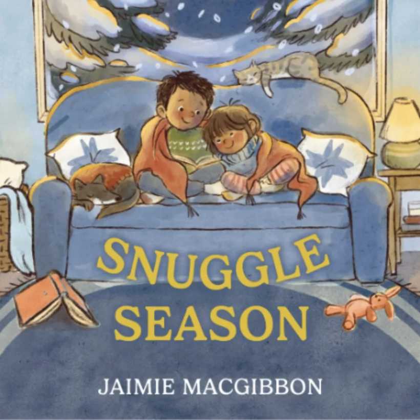 The front cover of the picture book Snuggle Season, showing two siblings sitting on the couch wrapped up in a blanket next to their sleeping dog