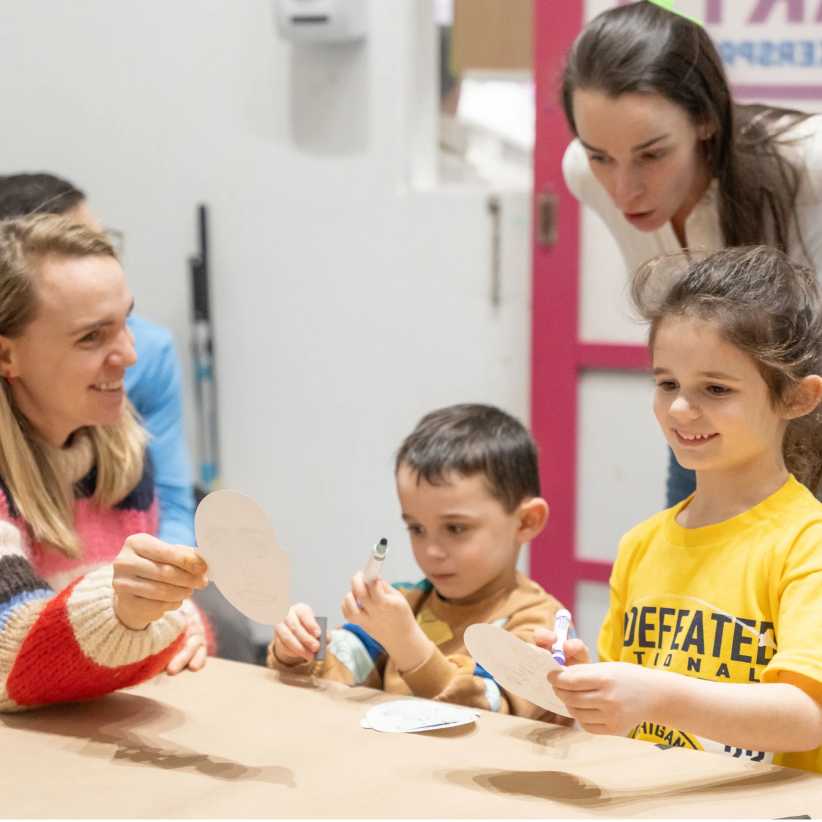 children doing crafts at a table with two moms