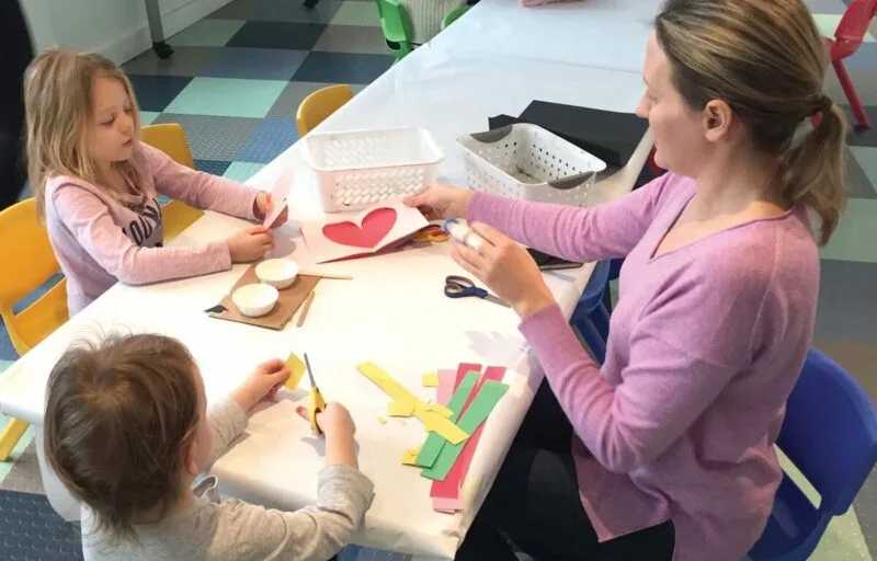 Parent sitting at a table making crafts with kids