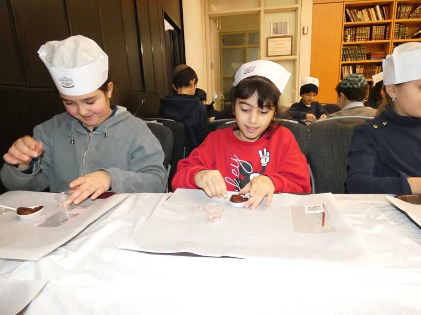 two kids at a table making chocolate.
