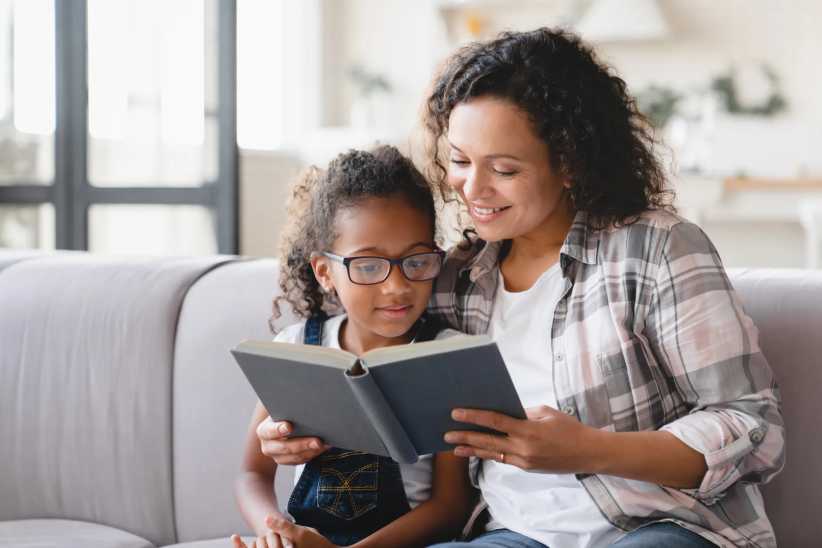 African-american mother mom reading book novel with daughter girl, 16 Must-Read Books for All Ages to Celebrate Women’s History Month