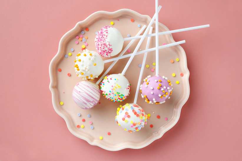 Various cake pops decorated with white and dark chocolate, sprinkled with sugar confetti, top view, Skip the Dye Kit This Easter — These 3 Ideas Are Way More Fun