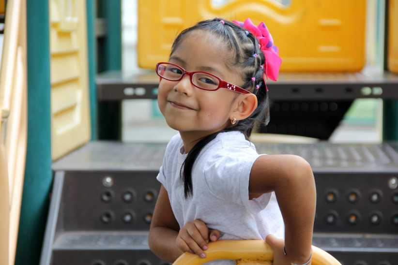 Little brunette latin woman girl with glasses plays outdoors in free games, happy, doing physical activity, 15 Best NYC Playgrounds for Kids & Families in 2026