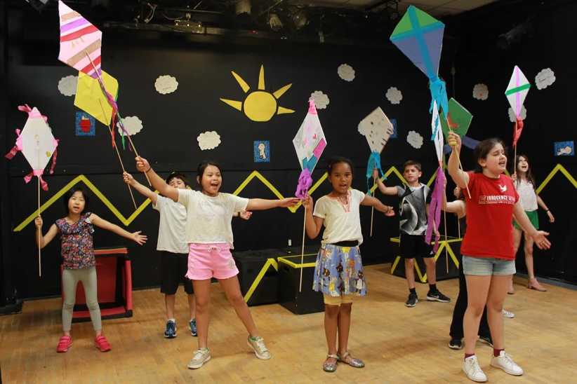 ChatGPT said:

Kids indoors holding colorful kites, joyfully stretching arms wide in a playful, decorated room with sun and clouds on the wall.