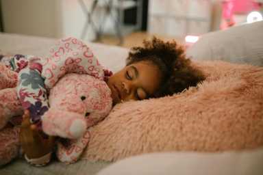 Young child sleeping and holding onto stuffed animal, back to school sleep