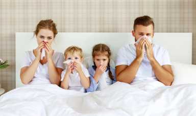 Mom, Dad, and two children sitting in bed with runny nose and fever as record-breaking Flu hits New York