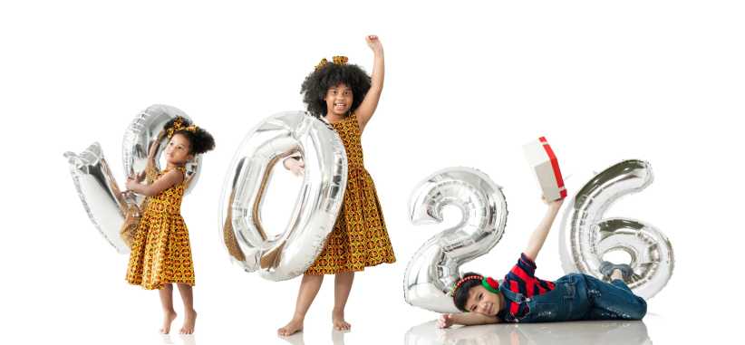 Three children holding silver balloons for the New Year 2026
