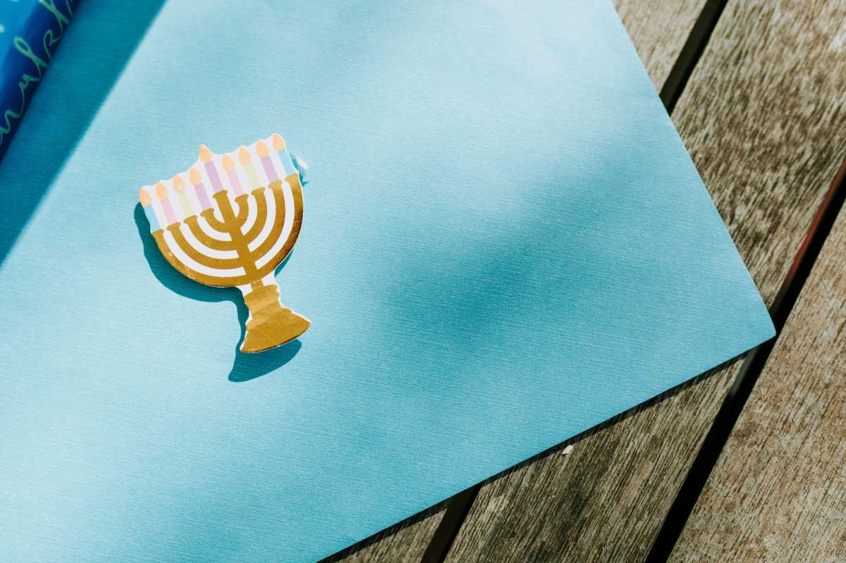 Blue wrapping paper unrolled with a small paper menorah on top.