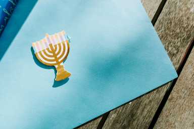 Blue wrapping paper unrolled with a small paper menorah on top.