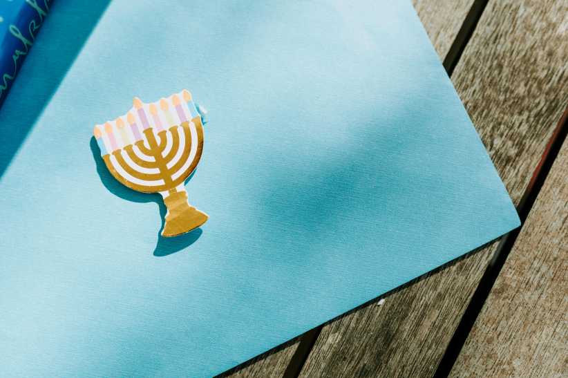 Blue wrapping paper unrolled with a small paper menorah on top.