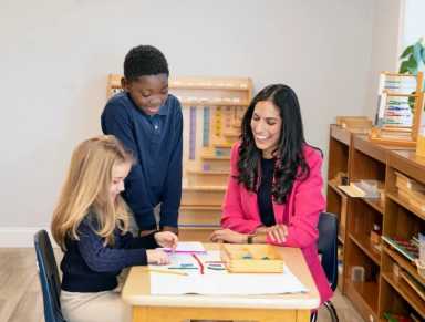 Teacher at Hudson Country Montessori School with her two students, teaching