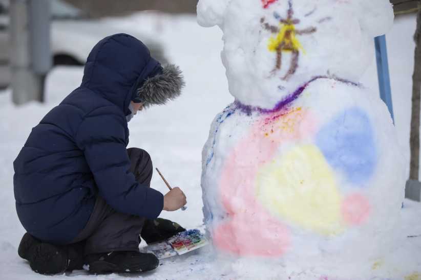 Fresh snow activities for kids. A boy paints a snowman on a winter day.