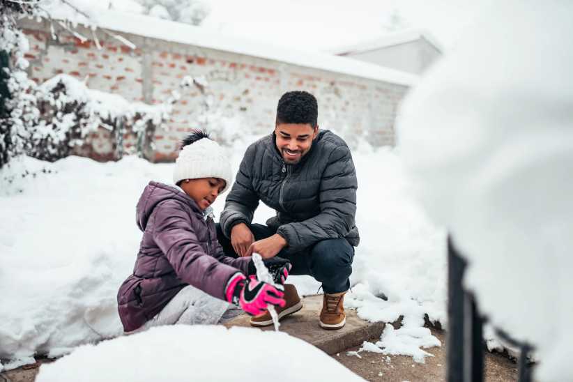 Fresh snow activities for kids. Father and daughter look for icicles in the backyard after a snowstorm