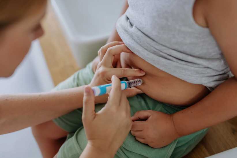 Type 1 diabetes, Mother of diabetic boy injecting insulin in his belly. Close up of young boy with type 1 diabetes taking insuling with syringe needle.