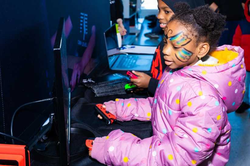 Little girl in a purple winter jacket playing a video game