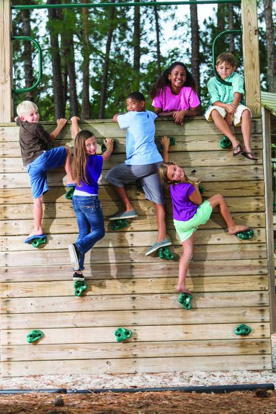Multi-ethnic children (6 to 11 years) on climbing wall at playground.