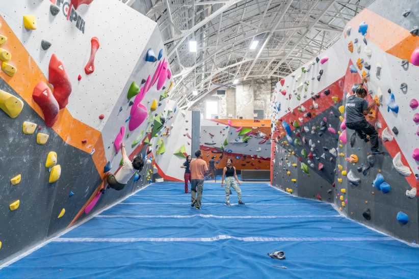 Climbers on colorful indoor bouldering walls at Movement Harlem rock climbing gym in NYC