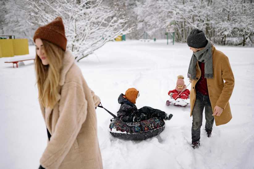Mom and Dad pulling kids on a sled