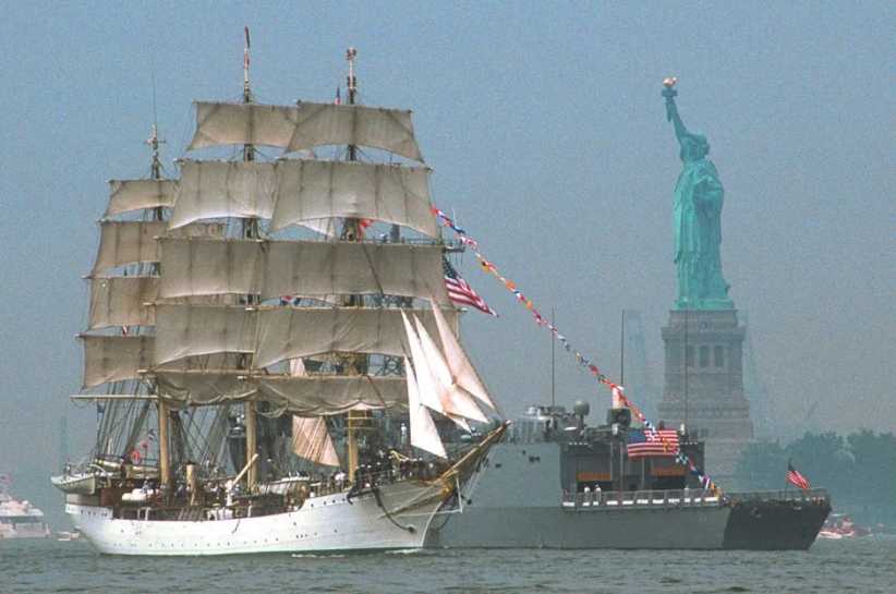 Tall ship in New York Harbor next to Statue of Liberty