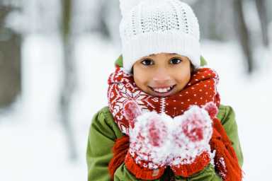 cute african american child showing white snow an smiling at camera in winter forest, Mayor Mamdani Announces NYC Schools Closed Monday for First Snow Day Since 2019