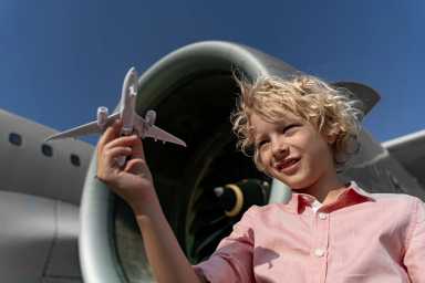 Aviation Activities for Kids Near NYC: Museums, Plane Watching & More - Kid playing with an airplane toy in front of an airplane engine