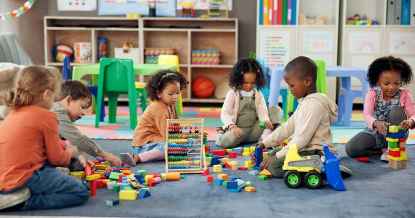 Kids, students and play with blocks in classroom for learning, problem solving and creative activity. Children, toys and floor for education game, puzzle solution and motor growth in kindergarten, new Bronx charter school, Strive Charter School