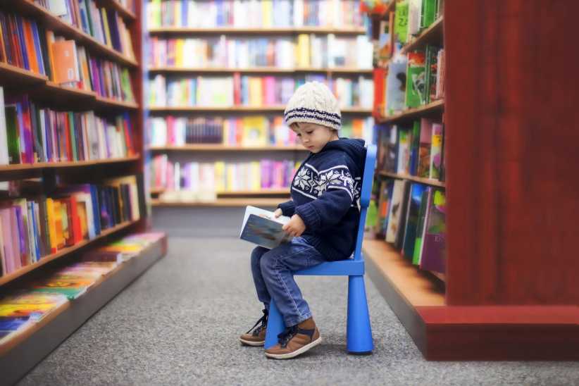 Adorable little boy, sitting in a book store, looking at books, February mid-winter break NYC
