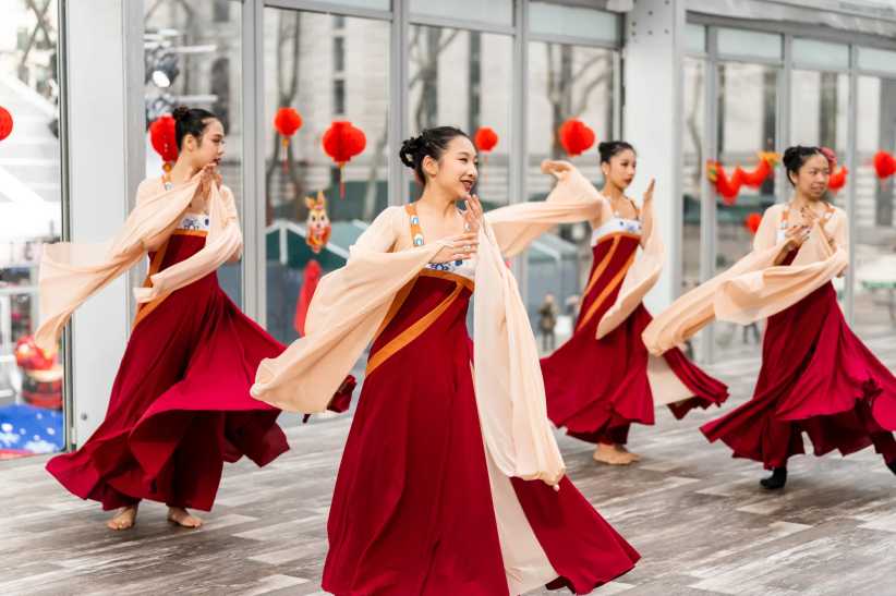 Women dancing in bright red dresses as part of the Lunar New Year celebration at Bryant Park