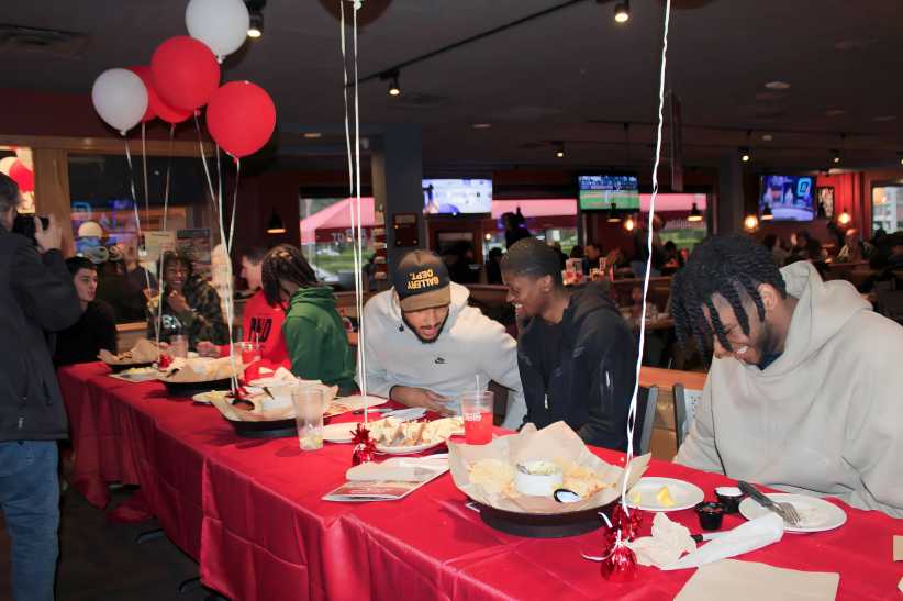 members of the st. john's men's basketball team sitting at a decorated table. 