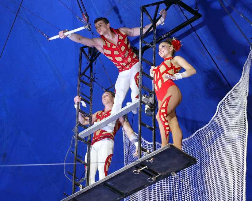 three trapeze artists on top of a platform ready to perform