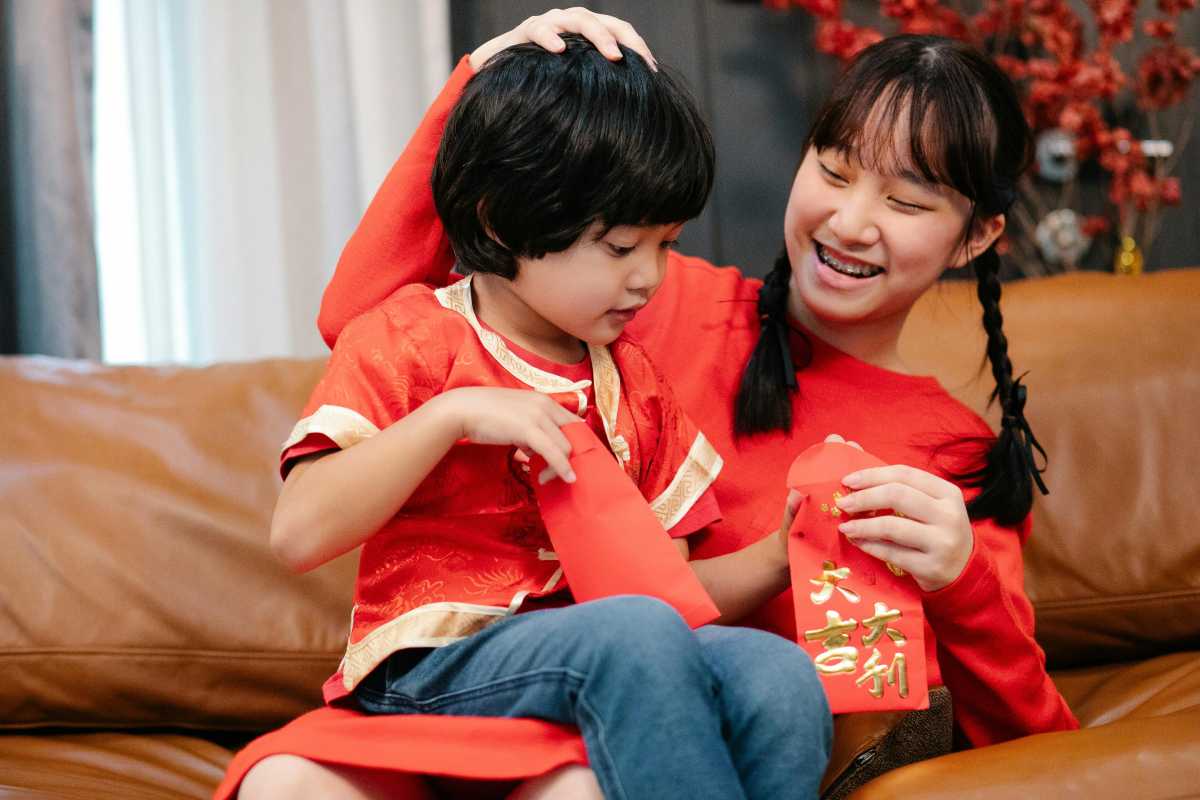 Brother and sister exchanging red envelops for lunar new year