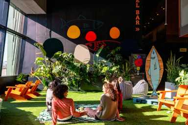 Moms and kids relaxing on the indoor lawn at Pier 57 indoor playground ni NYC
