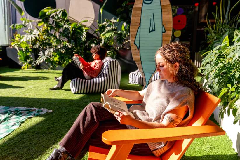 Moms relaxing and sitting in the sun while reading a book at indoor playground at Pier 57 in NYC