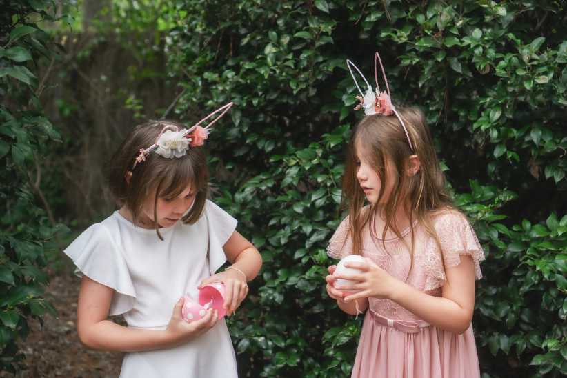 Two girls with an Easter egg container are looking at what is inside.