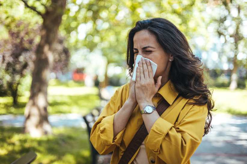 Portrait of woman in yellow top with napkin blowing nose, Why Spring Allergies Feel Worse in NYC: An Allergist Explains What Families Should Expect
